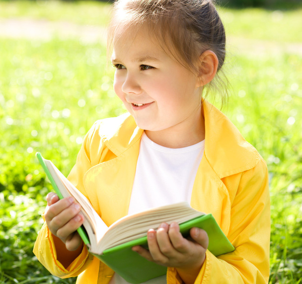 La niña está leyendo un libro al aire libre
 - Foto, imagen