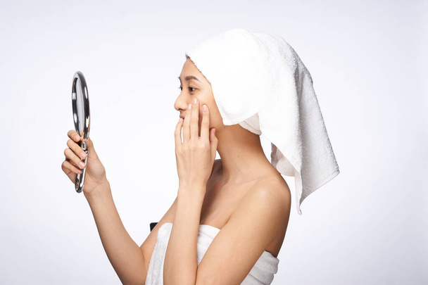 femme d'apparence asiatique après la douche regarde dans le miroir soins de la peau fond clair - Photo, image