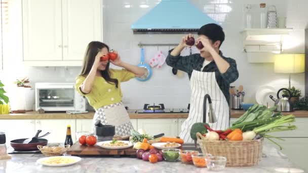 Asyalı çift, evdeki mutfakta romantik bir ortam yaratmak için birbirlerine yardım ediyorlar. Gençler karıştırmadan önce ahşap bir kasede malzemeleri karıştırmak için birlikte çalışırlar.. - Video, Çekim