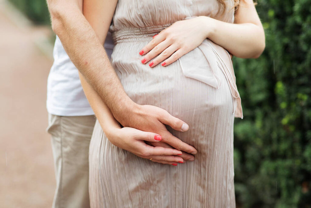 Man Hands Hug Pregnant Woman by Belly Close up Photography (em inglês). Ficando bela menina grávida vestida em vestido. Futuros Pais e Parto Horizontal - Foto, Imagem
