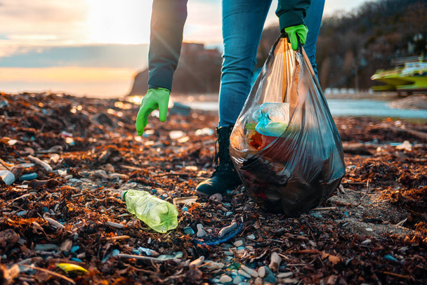 Доброволець збирає сміття на багнистому пляжі. Зблизька. Концепція дня Землі та охорони навколишнього середовища. - Фото, зображення