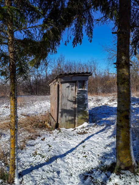 Kylpyhuoneen kuivakäymälä maaseudulla talvella. Vanha puusta valmistettu wc (wc) Latviassa maaseudulla. - Valokuva, kuva