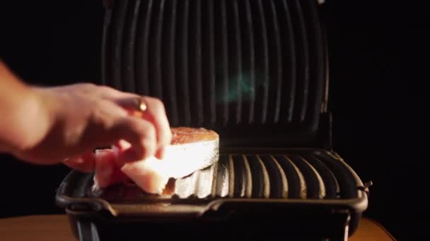Hombre chef caucásico prepara una cena saludable y sabrosa y parche de pescado fresco. El cocinero a mano pone filetes de salmón rojo en el plato de la parrilla. Vista lateral en frente - Metraje, vídeo