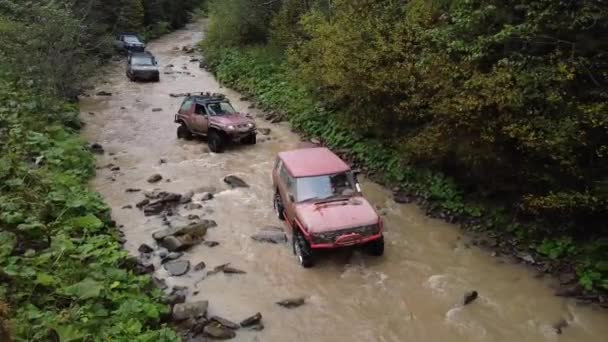  Diversi SUV stanno guidando lungo il fiume tra le pietre - Filmati, video