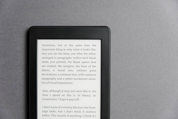 Szekrény kép egy elektronikus olvasó szöveggel a képernyőn egy szürke felületen. A technológia és a modernitás fogalma. Fénymásolós kép. - Fotó, kép
