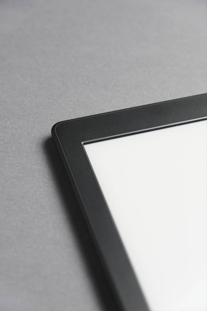 Close-up beeld van een elektronische lezer met blanco scherm op een grijs oppervlak. Begrippen technologie en moderniteit. Afbeelding met kopieerruimte. - Foto, afbeelding