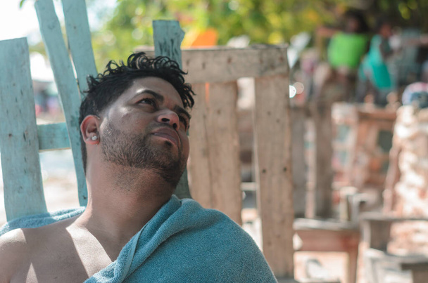 Dominik Cumhuriyeti 'nden esmer Latin bir adam plajda havluyla dinleniyor ve şöyle düşünüyor: - Fotoğraf, Görsel