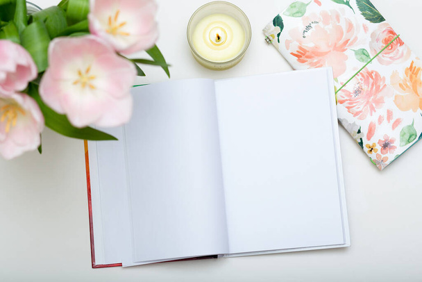 Still life, business or education concept. Top view of open notebook with blank pages and flowers on white background, mock up, template - Photo, Image