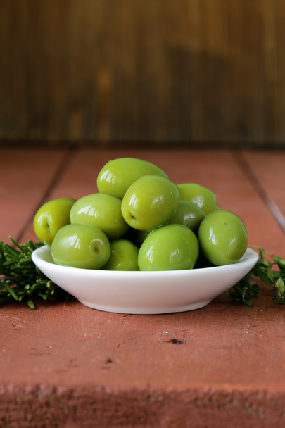 Green marinated olives in bowl on a wooden table - Valokuva, kuva