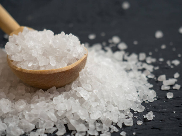 морская соль, куча морской соли в деревянной ложке на старом деревянном фоне крупным планом - Фото, изображение