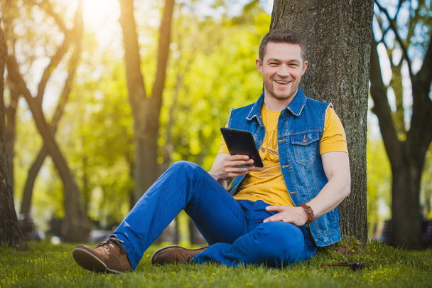 Handsome young man with tablet in the park - Foto, immagini