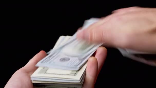 Maschio mani spargimento Stack di 100 US Dollaro bollette su sfondo nero. Soldi. 4K - Filmati, video