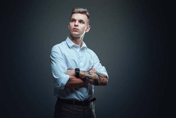Handsome hipster guy wearing white shirt looks away in dark background - Photo, Image