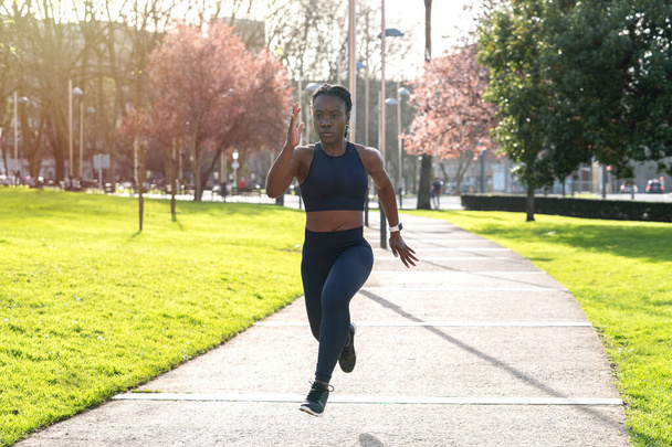 negro afro chica corriendo en un público parque al atardecer - Foto, imagen