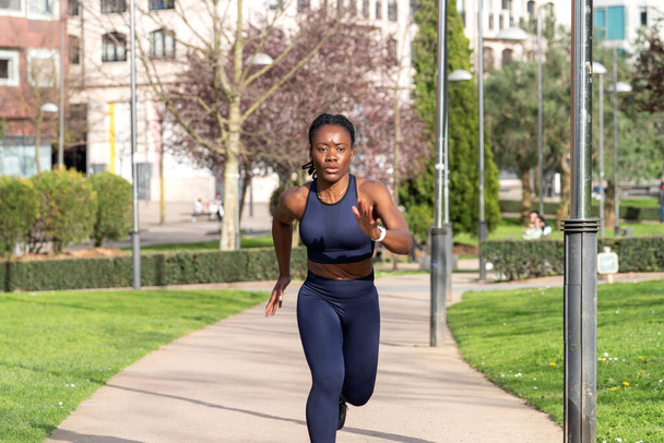 ランナーの格好をした公園を走る黒人アフロガール - 写真・画像