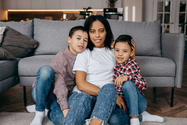 Heureuse mère de famille afro-américaine et deux fils qui s'amusent à la maison ensemble - Photo, image