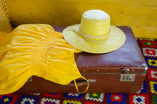 keltainen mekko ja olki hattu makaa vanha matkalaukku
 - Valokuva, kuva
