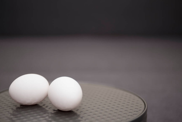 Ovos brancos em uma panela de bolo redonda close-up. Composição minimalista em um fundo cinza. - Foto, Imagem