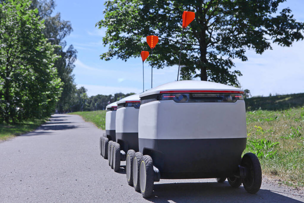 mozgó futárrobotok az úton. Cyber-futárok cirkálnak a járdán Észtországban. Másold le a helyet a tervezéshez. Modern szállítási koncepció - robotok szállítás. - Fotó, kép