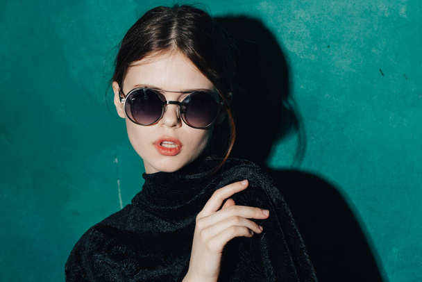 緑の背景の黒のセーターモデルのサングラスの女性 - 写真・画像