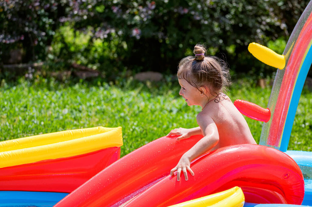Ευτυχισμένο κοριτσάκι που διασκεδάζει σε φουσκωτή πισίνα - Φωτογραφία, εικόνα