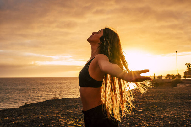 Фітнес щаслива і вільна молода жінка насолоджується заходом сонця після сеансу спортивних тренувань, приймаючи дихання
  - Фото, зображення
