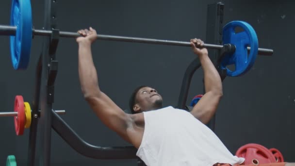 Fiatal izmos afro férfi gyakorló pad nyomja mellkas a padon súlyzóval - Felvétel, videó