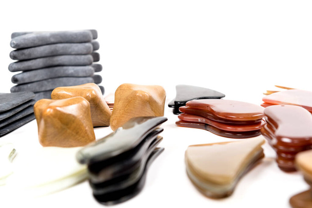 Big set of tools for spa treatments Jade massage stone on white background.Big set of Gua Sha jade scraping massage tool. Collection of different shape natural rose quartz stone. - Photo, Image
