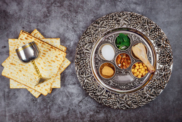 Jewish matzah bread with silver cup and flowers on wooden rustic background. Passover holiday concept - Photo, Image