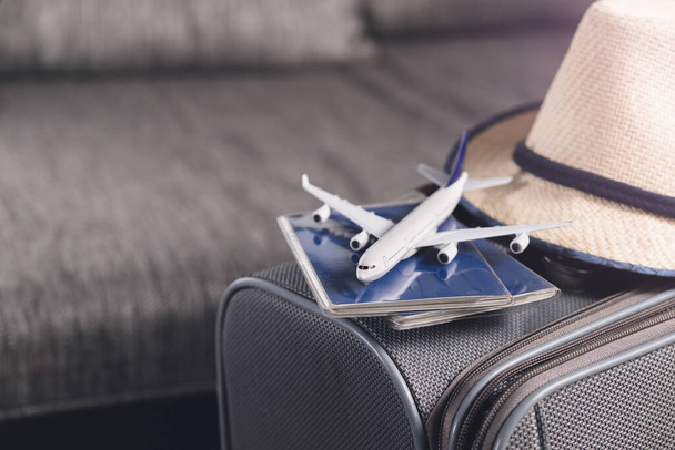 Koncepcja stylu życia i podróży po kwarantannie Paszporty, kapelusz i model samolotu na szarej walizce Przygotowywanie podróży lotniczych - Zdjęcie, obraz