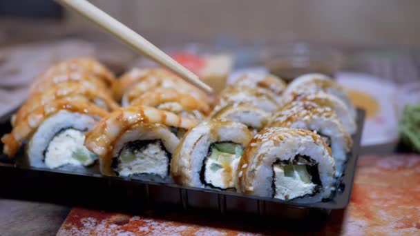 Las manos femeninas toman rollos de sushi recién preparados, con ayuda de palos de bambú. 4K - Metraje, vídeo