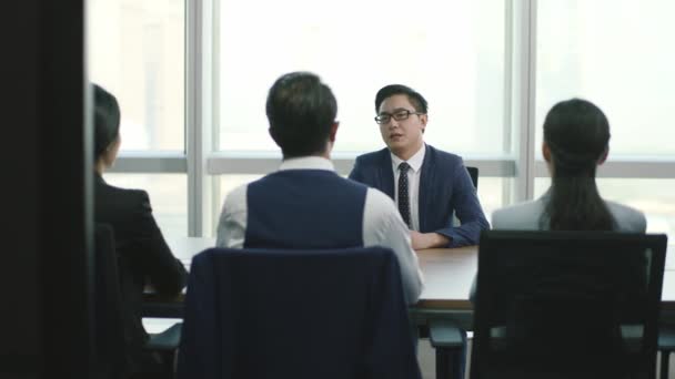 arrogante jonge Aziatische zakenman wordt geïnterviewd door een groep HR-leidinggevenden in een conferentieruimte van moderne bedrijven - Video