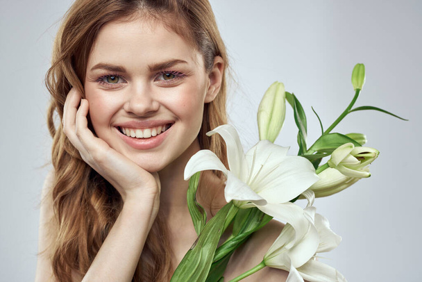 meisje met bloemen bijgesneden uitzicht portret close-up lente kale schouders heldere huid make-up - Foto, afbeelding