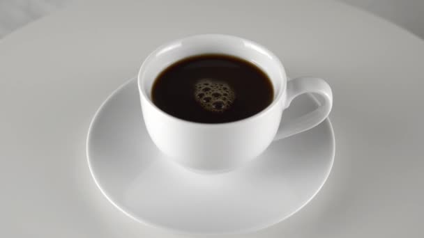 Weiße Kaffeetasse auf Rotationstisch, weißer Hintergrund. Espresso-Kaffee aus nächster Nähe - Filmmaterial, Video