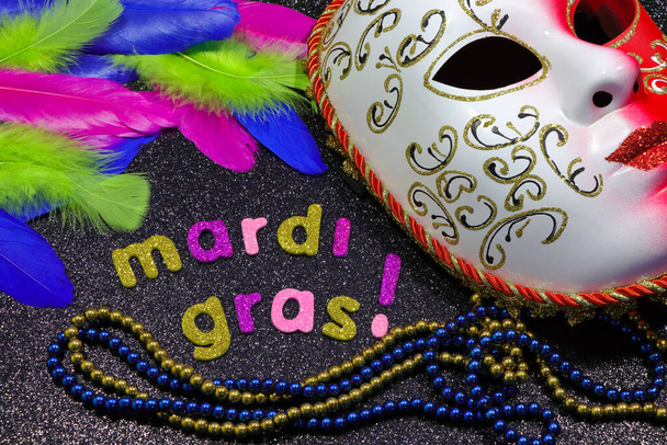 Mardi Gras szöveg és gyöngyök maszkkal és tollal - Fotó, kép