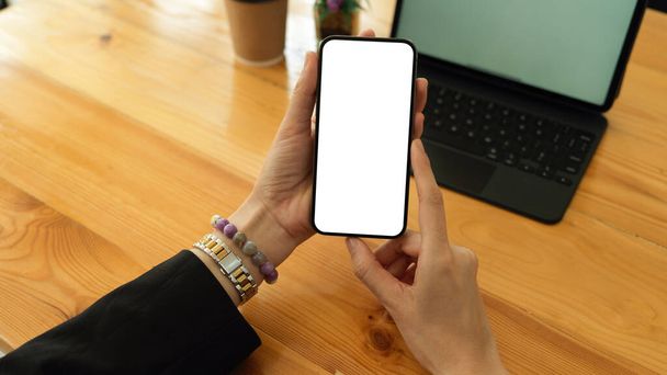Visão superior de mãos de empresária segurando smartphone e mostrando simular a tela para a câmera, cortando caminho - Foto, Imagem