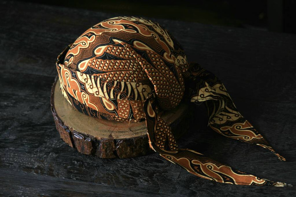 ένα παραδοσιακό κάλυμμα κεφαλής που ονομάζεται Blangkon τυπικό της Ινδονησίας Java. Αυτό το κάλυμμα κεφαλής φοράει ύφασμα μπατίκ και φοριέται για έθιμο ή εκδηλώσεις μόδας. - Φωτογραφία, εικόνα