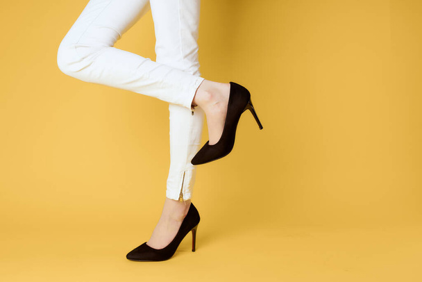 Pies femeninos zapatos negros ropa de moda estudio fondo amarillo - Foto, imagen