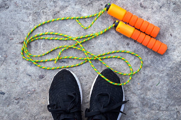 Спортивна стрибка мотузка біля ніг спортсмена в кросівках
 - Фото, зображення