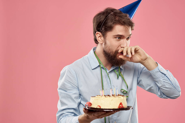 Bearded man with cake on pink background birthday party corporate emotions model loneliness - Photo, Image
