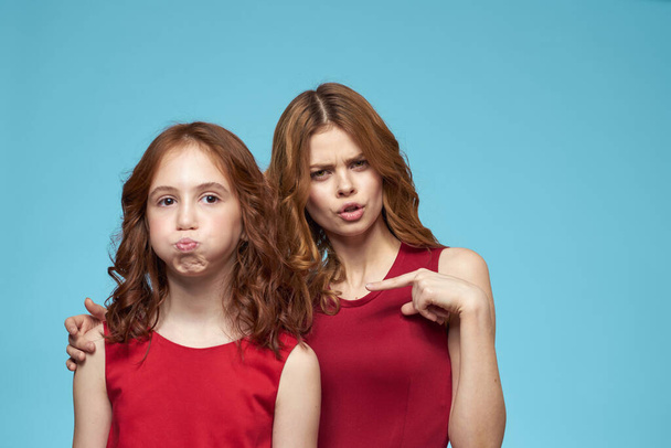 Anya és lánya piros ruhák szórakoztató életmód szórakoztató stúdió kék háttér - Fotó, kép
