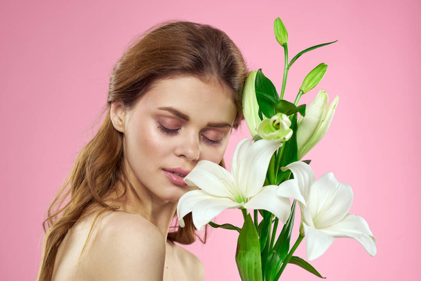 Portrait of a beautiful woman with white flowers in her hands on a pink background Copy Space cropped view - Foto, Bild
