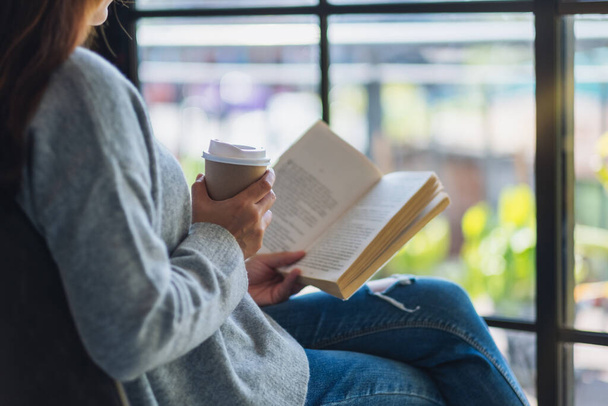Close-up beeld van een vrouw lezen boek en het drinken van koffie in de ochtend - Foto, afbeelding
