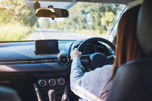 Imagem de perto de uma mulher segurando o volante enquanto dirige um carro na estrada - Foto, Imagem