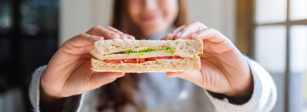 Fechar a imagem de uma mulher asiática segurando e comendo sanduíche de trigo integral  - Foto, Imagem