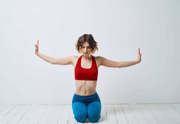 Woman in sportswear on a light background gestures with her hands yoga asana - Фото, зображення