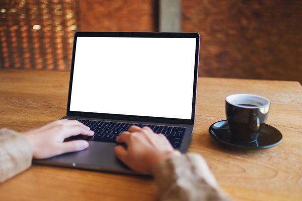 Wizerunek kobiety używającej i wpisującej na laptopie biały ekran z filiżanką kawy na stole  - Zdjęcie, obraz