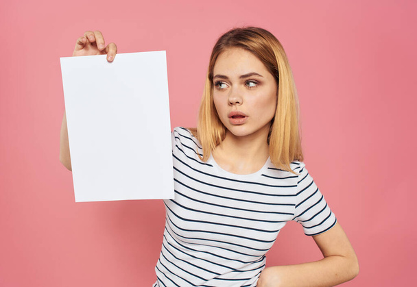 Женщина с белым листом бумаги на розовом фоне рекламный макет - Фото, изображение