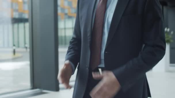 Close-up arc shot of hands and midsection of two anonymous Caucasian and black businessmen in formal suits and ties greeting each other in hallway of office building, shaking hands and talking - Footage, Video