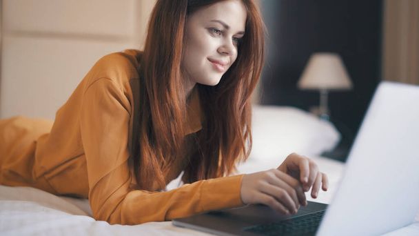 emotionele vrouw in de slaapkamer liggend op de bank met een laptop communiceren - Foto, afbeelding